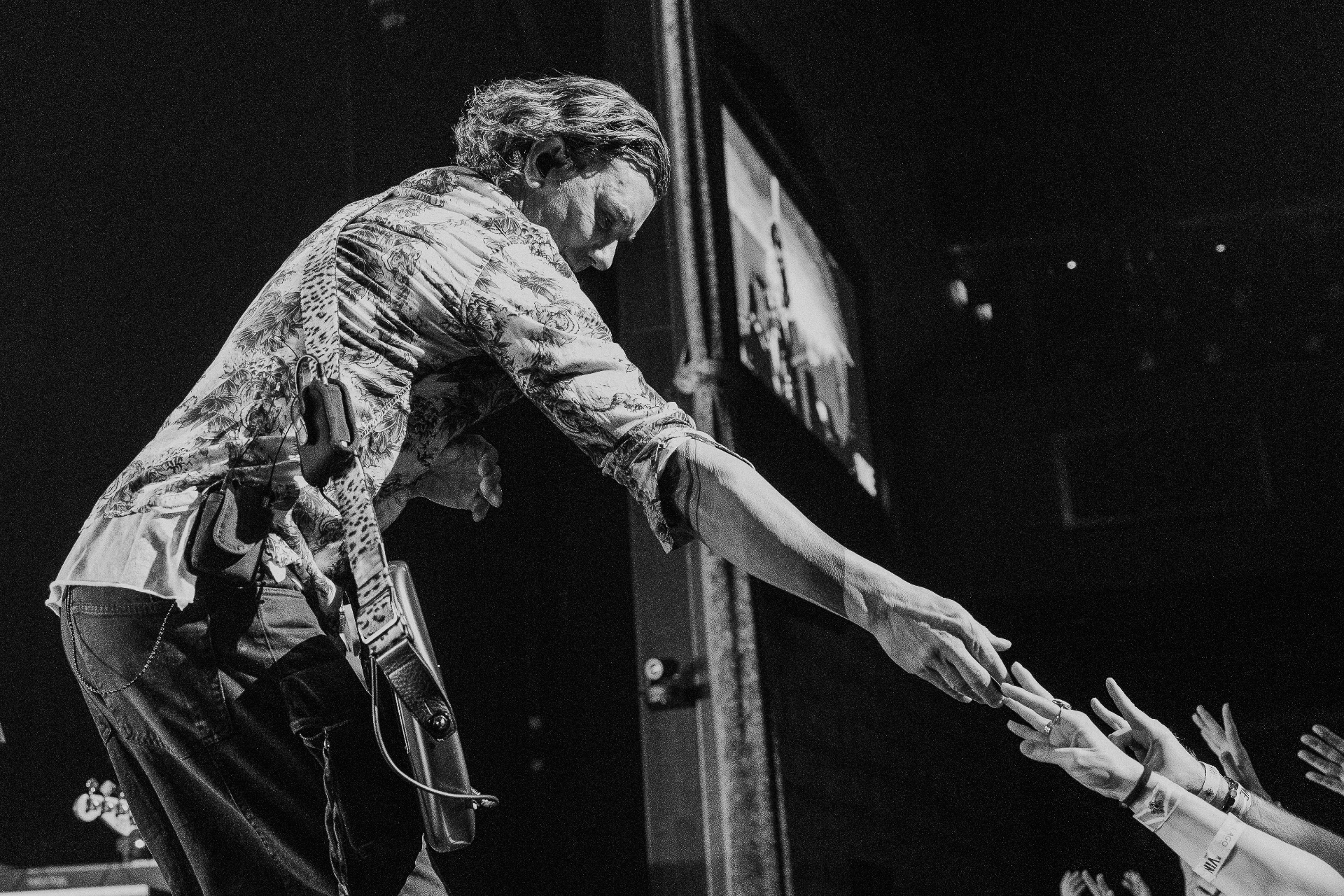 Performer reaching out to the crowd from the stage during a live concert