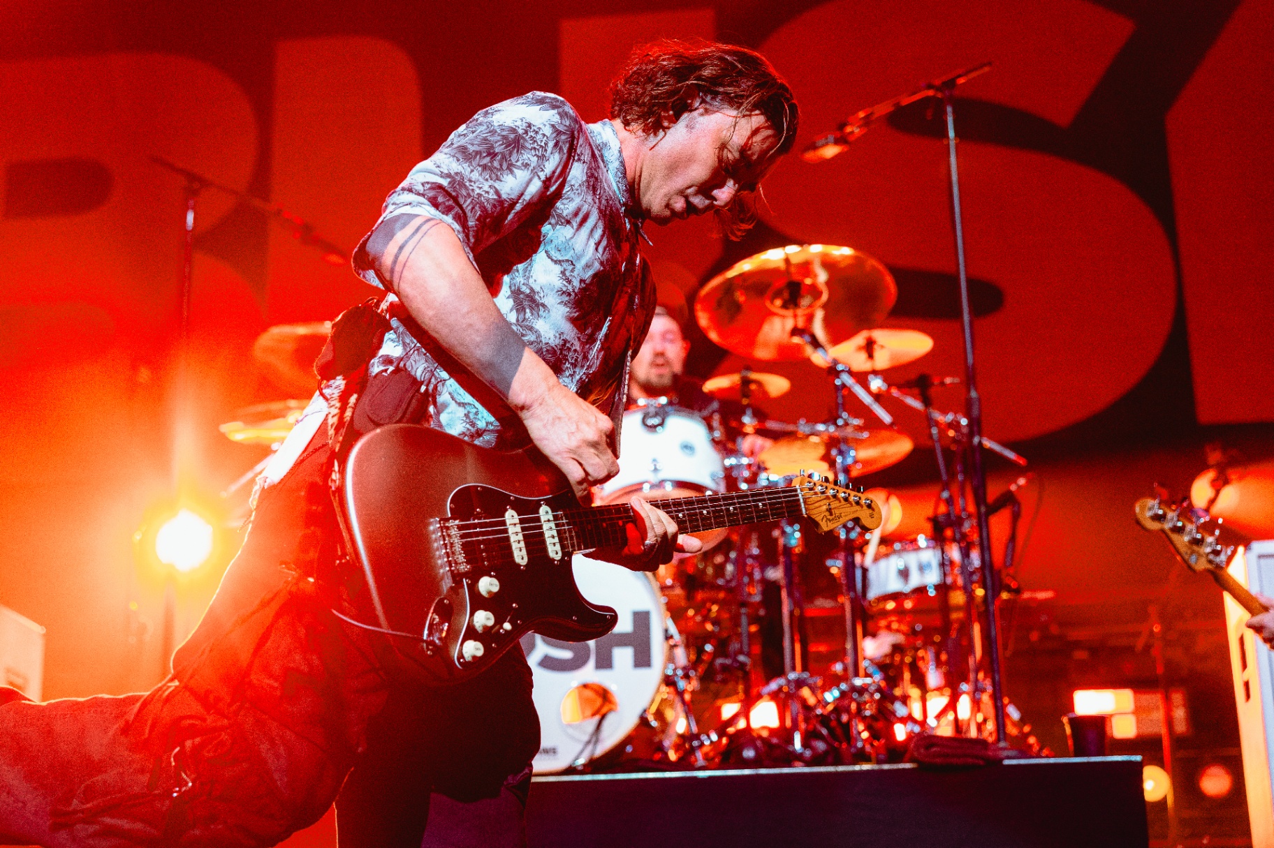 Bush guitarist mid-performance under red stage lights